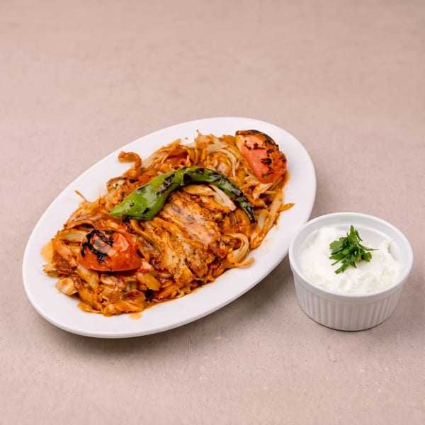 Chicken doner kebab with grilled tomatoes, green pepper, and a side of yogurt sauce.