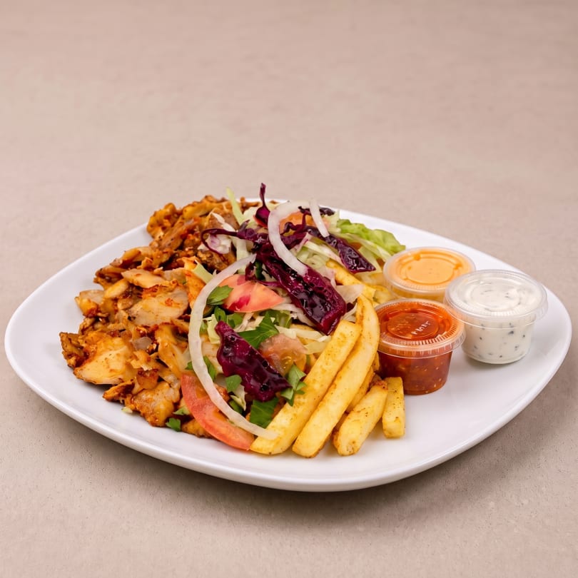 A white plate with chicken shawarma, french fries, salad, and three dipping sauces.