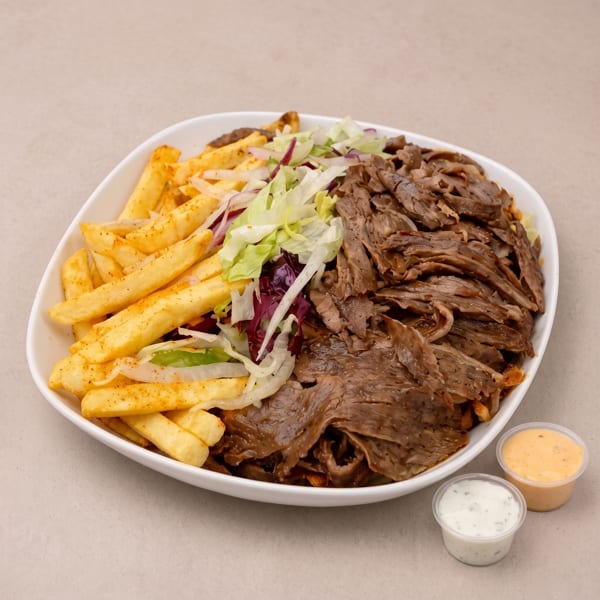 A white platter of döner kebab meat, french fries, and salad, with two sauce cups.